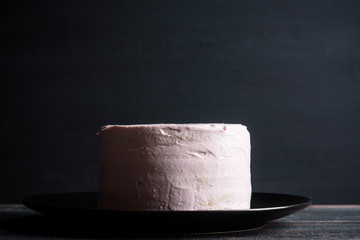 Pink creamy cake on the wooden background
