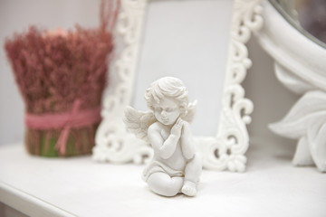 statuette of an angel on a white table with flowers