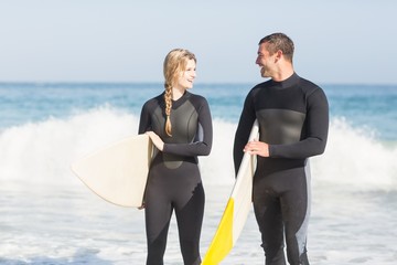 Couple with surfboard walking on the beach