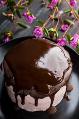 Pink creamy cake with flowers on the wooden background. Selective focus.