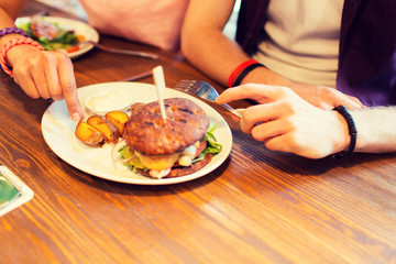 close up of friends hands sharing burger at bar