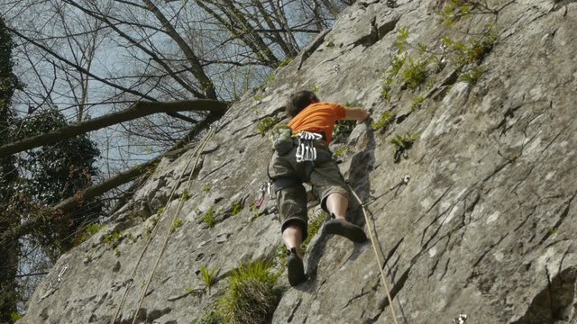 Male rock climber securing with rope. Low angle view.
