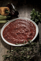 piatto di salsa al pomodoro con vari ortaggi e profumi intorno