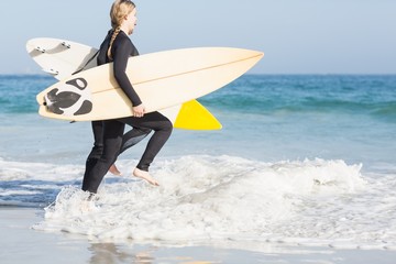 Woman with surfboard running towards sea