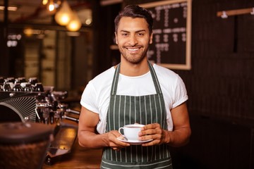 Smiling barista holding coffee in a cafe