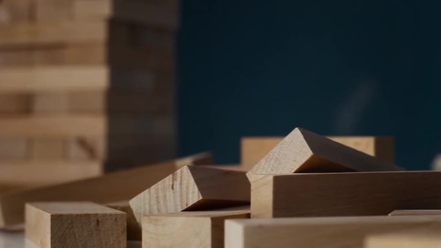 Closeup hand girl take one block on the tower from wooden blocks, dark tone.