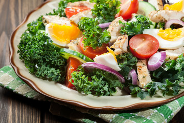 Fresh salad with chicken, tomatoes, eggs and lettuce on plate
