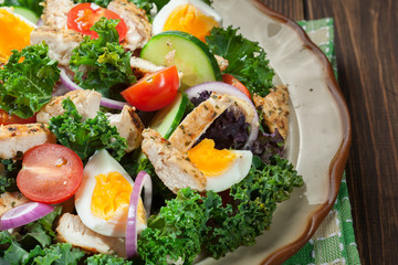 Fresh salad with chicken, tomatoes, eggs and lettuce on plate