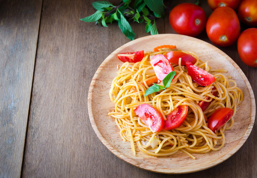 Pasta spaghetti with tomatoes, cheese and basil on rustic wooden background