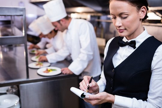 Waitress with note pad in commercial kitchen