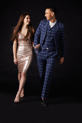 Fashionable young couple walking together arm in arm