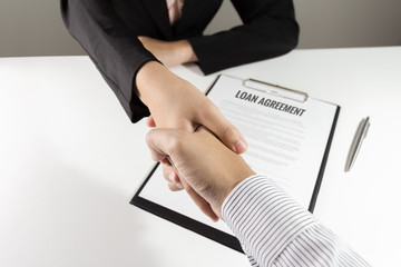 Businessman and businesswoman handshake over loan agreement document