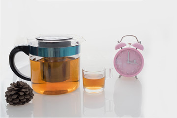 Hot tea set with glass cup and glass pot on isolated background with pink clock on tea time at 3 o’clock  / Hot tea set with glass cup and pot on isolated background at tea time