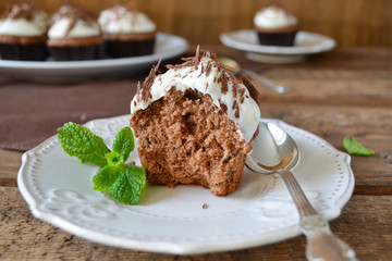 Chocolate cupcakes with cream and chocolate on a wooden backgrou