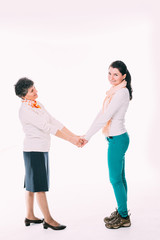 Senior woman holding hands with young female
