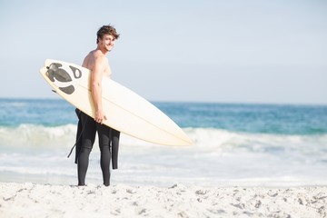Surfer walking on the beach with a surfboard