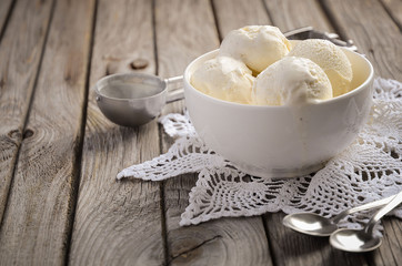 Vanilla ice cream in white bowl on rustic wooden background