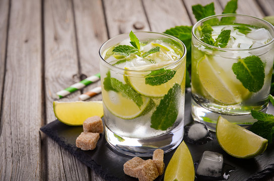 Fresh mojito cocktail with lime and mint on rustic wooden background