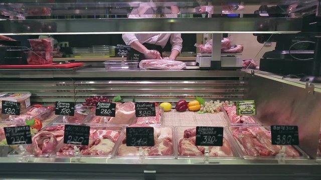 Beef and pork meat with price tags in the shop window of meat store. Seller working. Russia.Lockdown shot.