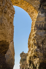alte Steinbrücke zwischen zwei schroffen, gelben Klippen an der Algarve