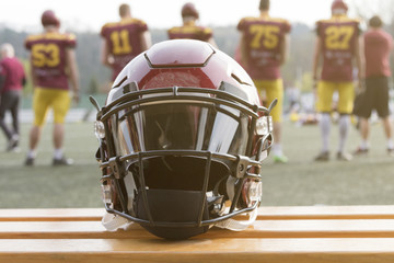 American football helmet on the bench and team in the background 