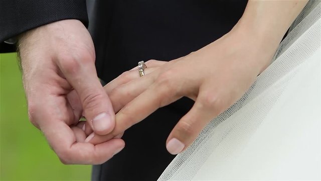 Groom holds bride's hand gently.