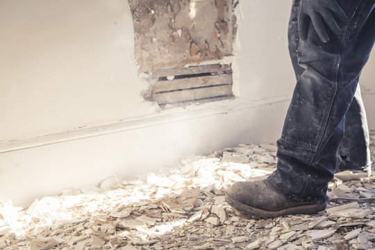 Construction worker standing in rubble of wall