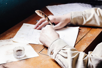 Rustic handsome young writer writing with quill on paper parchme