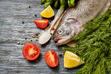 Raw trout and ingredients for cooking on a  dark wooden background. Healthy food  concept
