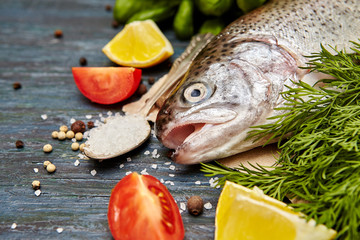 Raw trout and ingredients for cooking on a  dark wooden background. Healthy food  concept