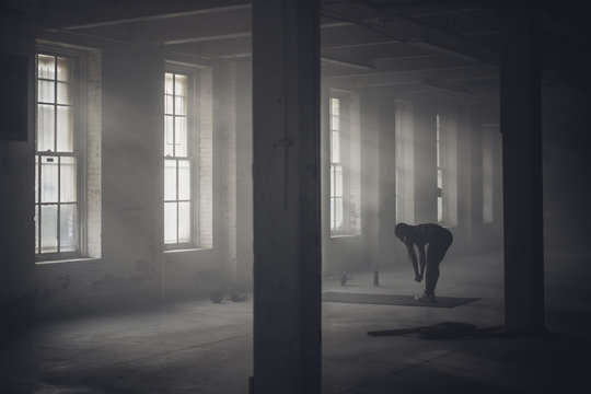 Black woman stretching in dark gym