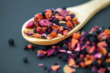 assortment of dry tea in wooden spoon, on black background