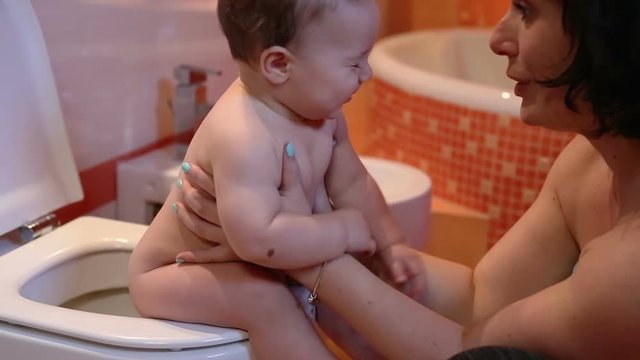 Mother is teaching a child to pee on the toilet
