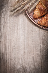 Composition of wheat rye ears rolls brass tray on wooden board
