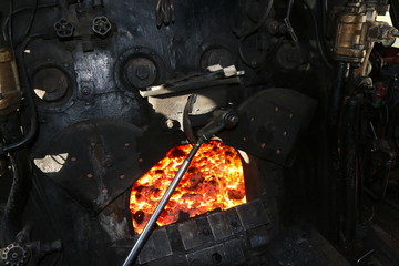 Open fire chamber of a very old steam locomotive with red-hot charcoal