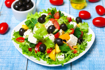 Obraz na płótnie Canvas Greek salad with fresh vegetables, feta cheese and black olives on a wooden background