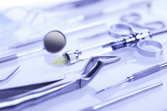 Closeup of dental syringe, dental mirror and dental forceps on white background