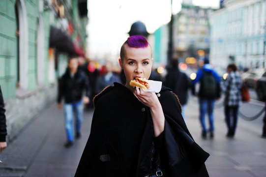 beautiful young woman eating a hot dog on the way to the street