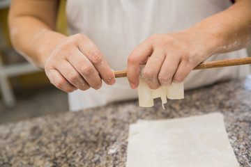 Hands baking dough with rolling pin on wooden table