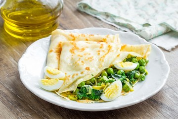 Pancakes, crepes stuffed with green peas, spinach, leeks, Russia