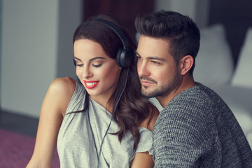 Happy young couple listening music at home