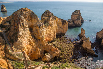 Traumhafte leuchtende Felsen an der Algarve Küste mit menschenleeren Stränden und blühenden...