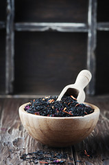 Fototapeta na wymiar Delicious black tea with petals on the wooden table