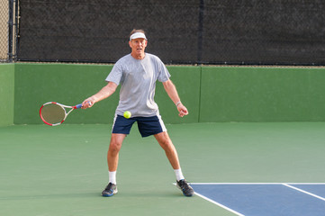 Senior age man showing perfect set up on forehand. 