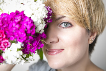 Fototapeta premium Close-up portrait of young beautiful stylish woman with gorgeous spring flowers . Flowers cover the half of the face