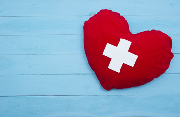 red heart with a white cross on blue background