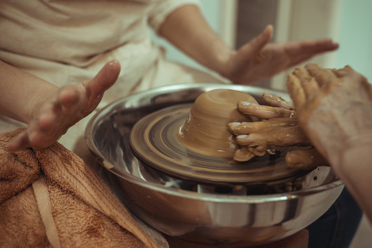 teacher and student work on the potter's wheel