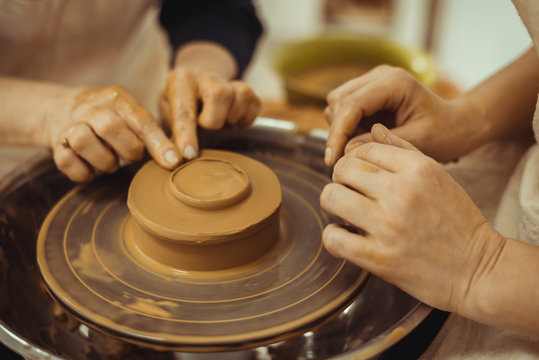 teacher and student work on the potter's wheel