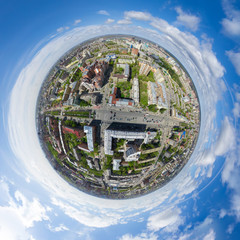 Aerial city view with crossroads and roads, houses, buildings, parks and parking lots, bridges. Copter shot. Little planet mode. Full sphere.