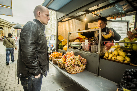 Caucasian man buying produce at fruit kiosk